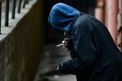 A person holds a lighter in an alleyway while smoking in the US state of Oregan in 2024