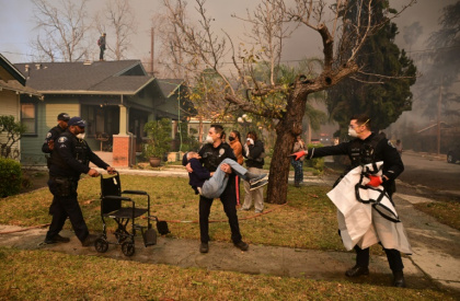 Police officers remove an elderly resident from her home during the Eaton Fire in Altadena, California