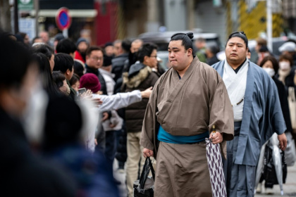 People gather at the entrance of Tokyo's Kokugikan arena for the arrival of sumo wrestlers during the Grand Sumo Tournament