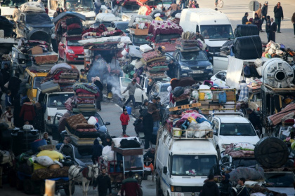 Displaced Palestinians wait along the Salah al-Din road in Nuseirat near the blocked Netzarim corridor, to cross to the northern part of the Gaza Strip