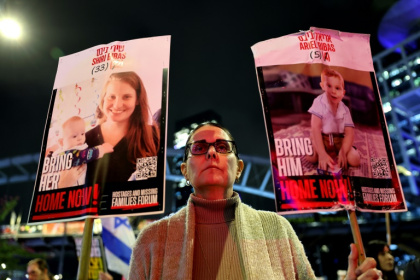 A demonstrator in Tel Aviv holds placards bearing pictures of members of the Bibas family