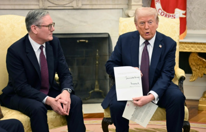 Donald Trump holds a letter from Britain's King Charles III during a bilateral meeting with British Prime Minister Keir Starmer in the Oval Office